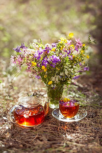 露天茶会。一个杯子和茶壶特写镜头在自然界在森林里。束鲜花
