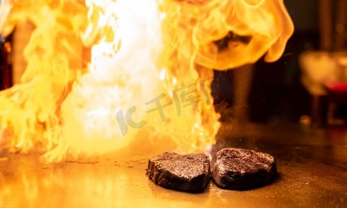 烹饪牛肉铁板烧食谱日本烤牛肉在烹饪锅使用刮刀有火焰在背景