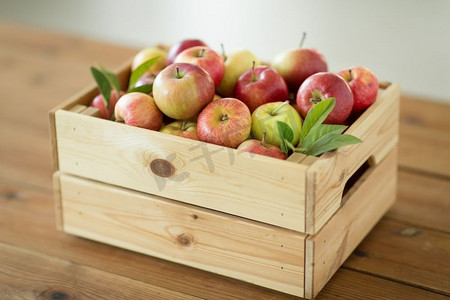 成熟的苹果摄影照片_水果，食物和收获概念—成熟的苹果在木箱上的桌子。成熟的苹果在木箱在桌子上