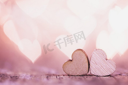两个手工制作的木心在美丽的粉红色散景背景。复古风格。Love Valentine s Day概念’两颗心在散景背景