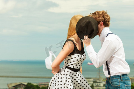 古风关系摄影照片_夏天幸福的爱情关系和约会概念—浪漫好玩的夫妇复古风格调情接吻在日期隐藏在帽子后面户外