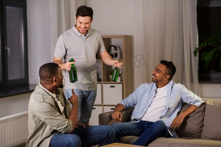 友谊、休闲和人的概念-快乐的男性朋友晚上在家喝啤酒。快乐的男性朋友晚上在家喝啤酒