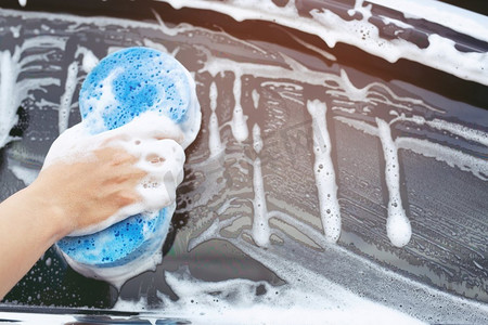 人们手握蓝色海绵洗车。	