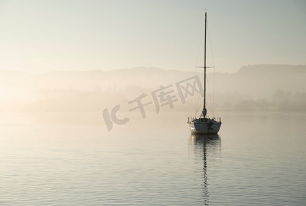 航行游艇的美丽的不插电风景图像坐在平静的湖水在湖区在和平的薄雾秋天日出