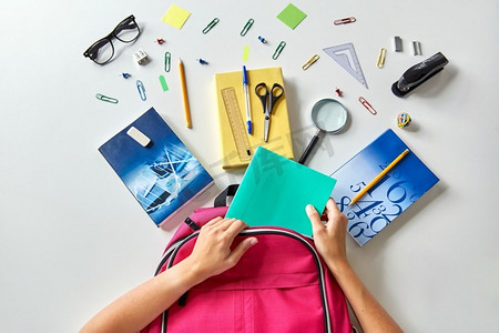教育和学习概念—手包装粉红色背包与书籍和学校用品表。手拿书包，书本和学习用品