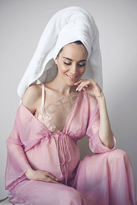 美丽的孕妇在粉红色的睡衣得到淋浴后的生活方式肖像。美好的早晨。美容和健康