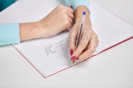 教育、学校和学习理念-学生女孩的手，用笔写到笔记本上。女学生用笔在笔记本上写字的手