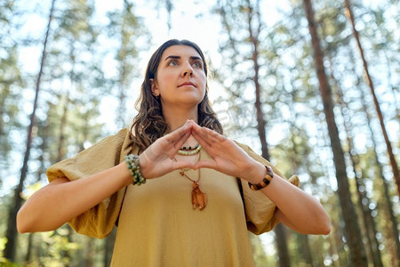 魔法,灵性和超自然概念-年轻女性或女巫在森林中做出权力手势的三角形