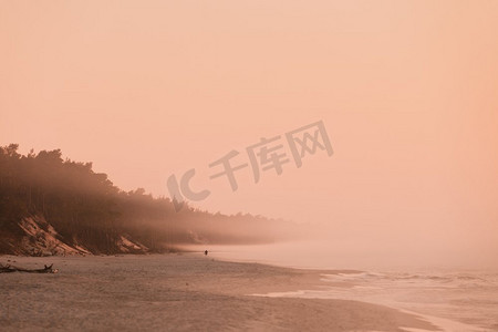 美丽的海岸线风景。海滩在早上雾天气，奶橙色的颜色。海滩在日出雾