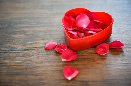 情人节爱心概念/打开红心盒，木质背景上装饰着红玫瑰花瓣