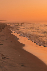 在橙色和金色色调中拍摄的日落时挥动的海水的特写。黑暗的气氛。日落时分挥动的大海