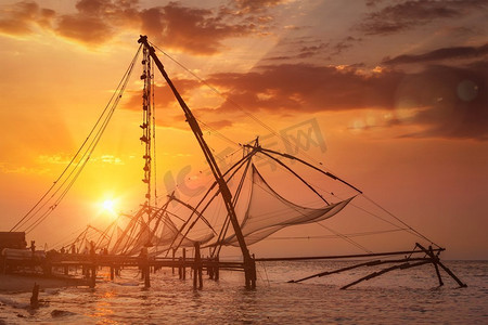 高知中国渔网日落。印度喀拉拉邦，科钦堡。有镜头闪光和光线泄漏。日落时分的中国渔网印度喀拉拉邦