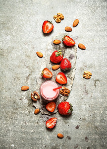 草莓冰沙加牛奶和坚果。在石桌上。草莓冰沙加牛奶和坚果。