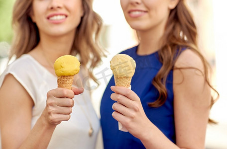 夏天，食物和人的概念—在城市吃冰淇淋的快乐妇女特写镜头。关闭快乐的妇女吃冰淇淋在城市