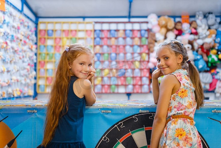 两个小女朋友玩在孩子射击画廊，游乐场在娱乐中心。室内游戏区，游戏室