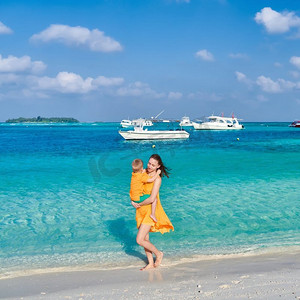 三岁的小男孩和妈妈一起在海滩上。暑假在马尔代夫度假。