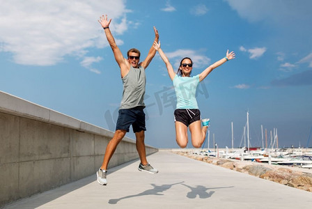 健身，运动和生活方式的概念—快乐的夫妇在运动服跳码头。快乐的夫妇在运动服跳码头