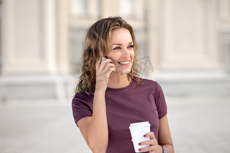 一位美女拿着手机，手里拿着一杯外卖咖啡。