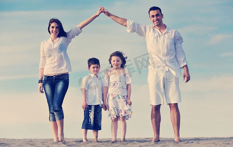 幸福的年轻家庭在海滩上玩得开心，在保护孩子的同时用双手展示回家的手势