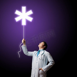 男医生。年轻男医生手持带有医学标志的气球