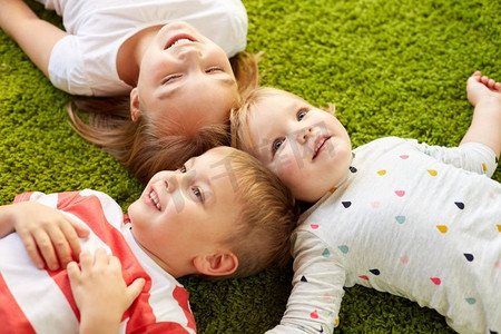 童年、休闲和家庭概念-快乐的小孩子躺在地板或地毯上。快乐的小孩子躺在地板或地毯上