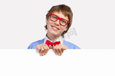 戴红眼镜的男孩拿着白色方块。小男孩笑着抱着白色方块的形象。刊登广告的地点