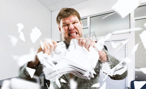 愤怒的商人在办公室撕纸堆。疯狂的商人与文件，坏情绪，压力