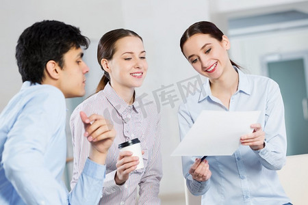 学生在合作中工作。三名学生一边喝咖啡，一边用笔记本电脑合作工作