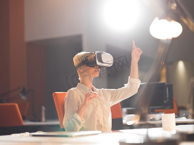 获得经验摄影照片_获得使用虚拟现实VR头戴式眼镜的经验的年轻女商人在深夜启动办公楼
