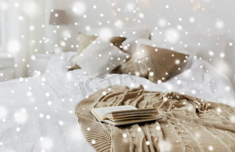 舒适的家和冬天的概念书在圣诞节的床上的卧室在雪上。圣诞之家卧室床上的书
