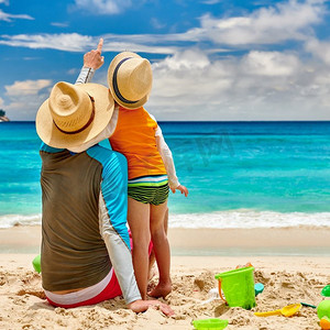 三岁的小男孩和父亲在海滩上。夏季家庭度假在塞舌尔，马埃岛。