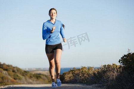 运动跑步者在海滩上慢跑锻炼。健康的女性健身模特沿着海洋慢跑
