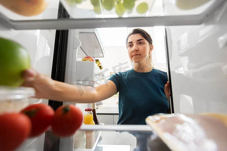 健康饮食，食物和饮食概念—妇女从冰箱在家庭厨房的苹果。女人从家里的冰箱里拿食物