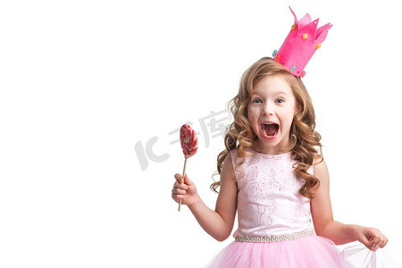 心冠摄影照片_美丽的小糖果公主女孩在冠拿着大粉红色心棒棒糖和尖叫孤立在白色。糖果公主女孩