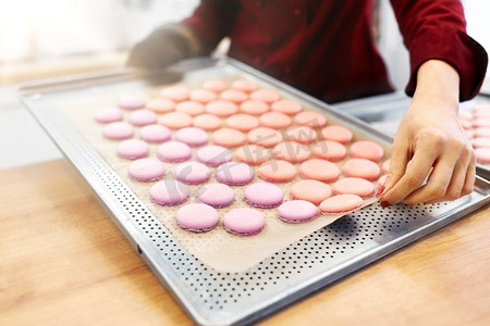 烹调、糖果和人概念-有马卡龙的厨师在烤箱托盘在面包店。厨师与马卡龙烤箱托盘在糖果