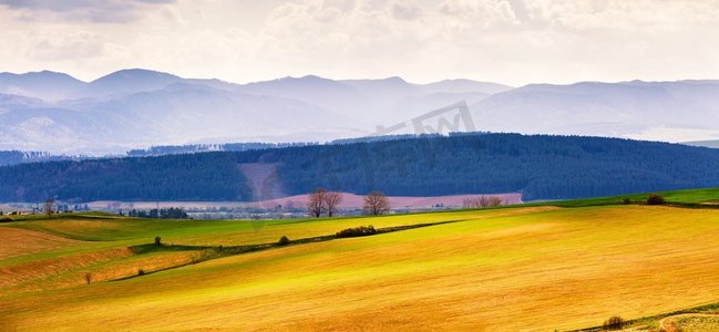 魔力设山丘摄影照片_春天的山丘、田野和草地景观。春天的斯洛伐克塔特拉斯山脉全景。