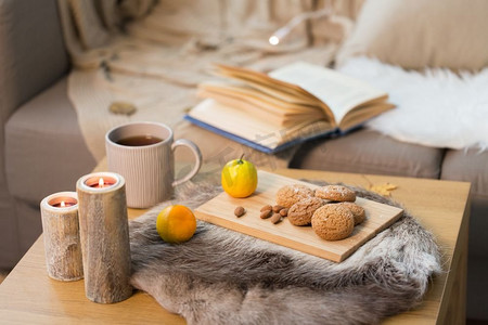 温馨舒适的家居概念--客厅的木桌上有燕麦饼干、柠檬茶和蜡烛。家里的桌子上有饼干、柠檬茶和蜡烛