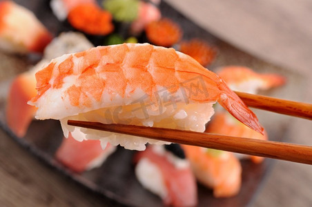 虾寿司由筷子举行从什锦寿司拼盘的背景