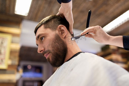 美容和人的概念-理发店里剃头直发的男人和理发师。留着剃须刀直发的男人和理发师