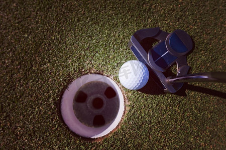 近摄推杆击中高尔夫球洞在课程。将高尔夫球击入洞