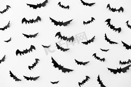 蝙蝠黑色摄影照片_万圣节，装饰和可怕的概念-成群的黑色纸蝙蝠在白色背景上飞翔。白色背景上的一群黑色纸蝙蝠