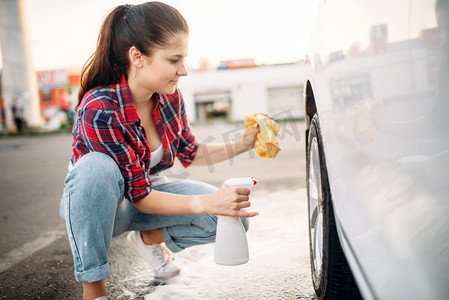 妇女用喷雾器、洗车器清洗汽车的车轮盘。女士自助洗车。夏季户外车辆清洁 