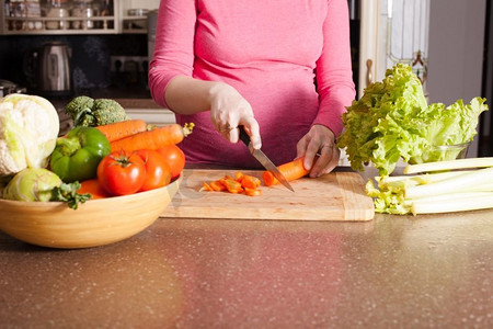 一位孕妇正在厨房里做菜。一名孕妇正在做饭