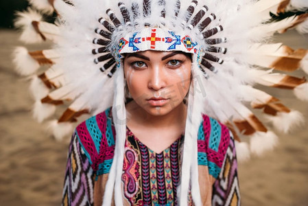 牛年头饰摄影照片_年轻的美国印第安妇女的脸，切罗基人，纳瓦霍人。用野鸟羽毛制成的头饰