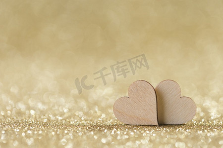 在明亮的金色光bokeh背景的两个小手工制作的木心情人节卡。两颗心在散景背景