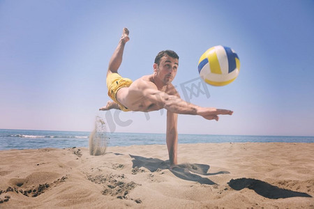 男子排球摄影照片_男子沙滩排球运动员在滚烫的沙滩上跳跃