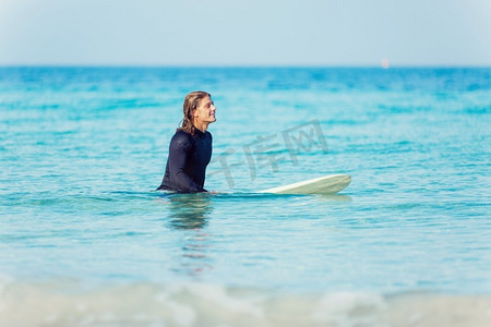 一名年轻的冲浪者在海滩上挥舞着冲浪板。准备好掀起波澜