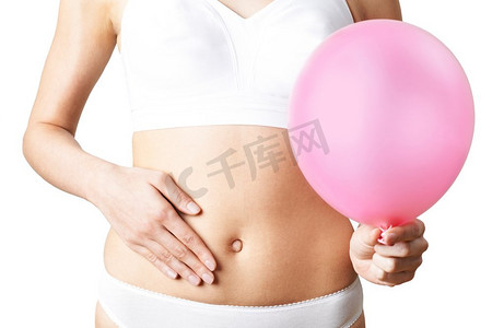 气球字61摄影照片_穿着内裤的女子手持粉色气球抚摸腹部的特写