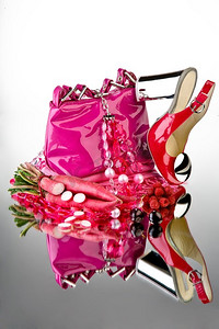 一个特写镜头的一个粉红色的钱包，红色的鞋，浆果和萝卜在镜子上。