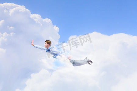 飞超人摄影照片_会飞的商人。年轻的超级商人在天空中高高飞行